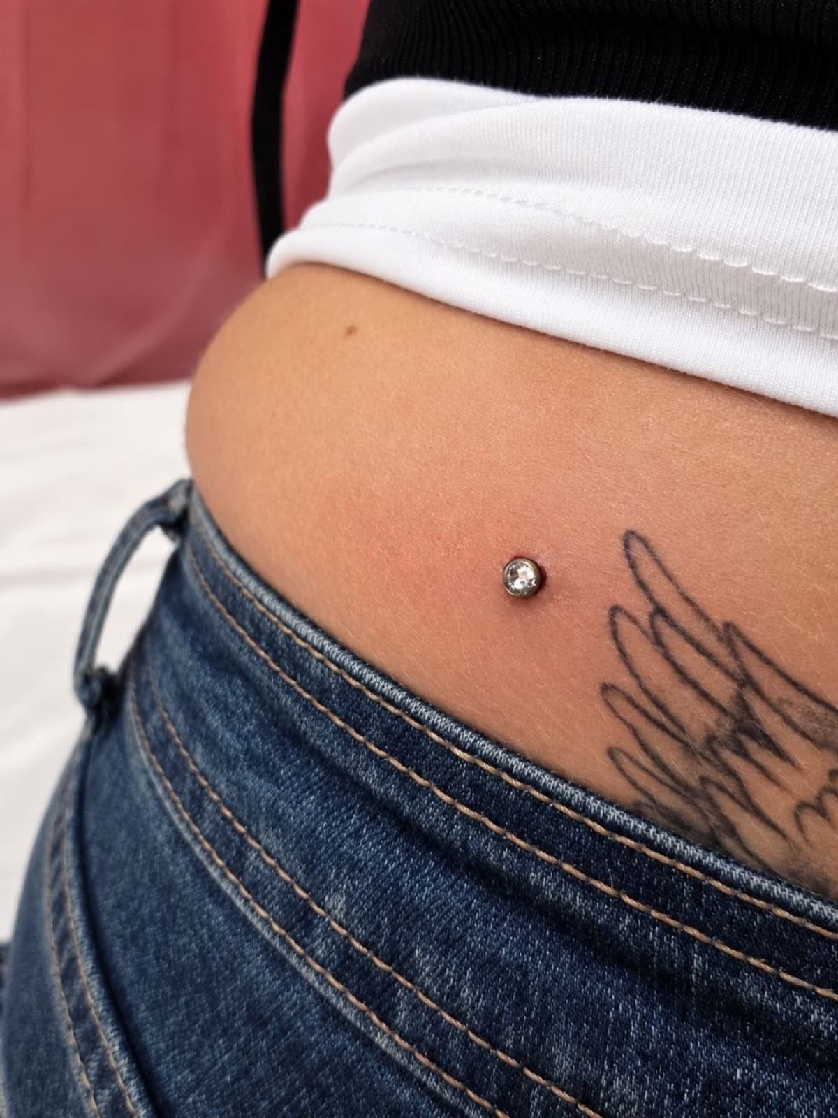 Single surface dermal piercing on the lower back with a crystal top