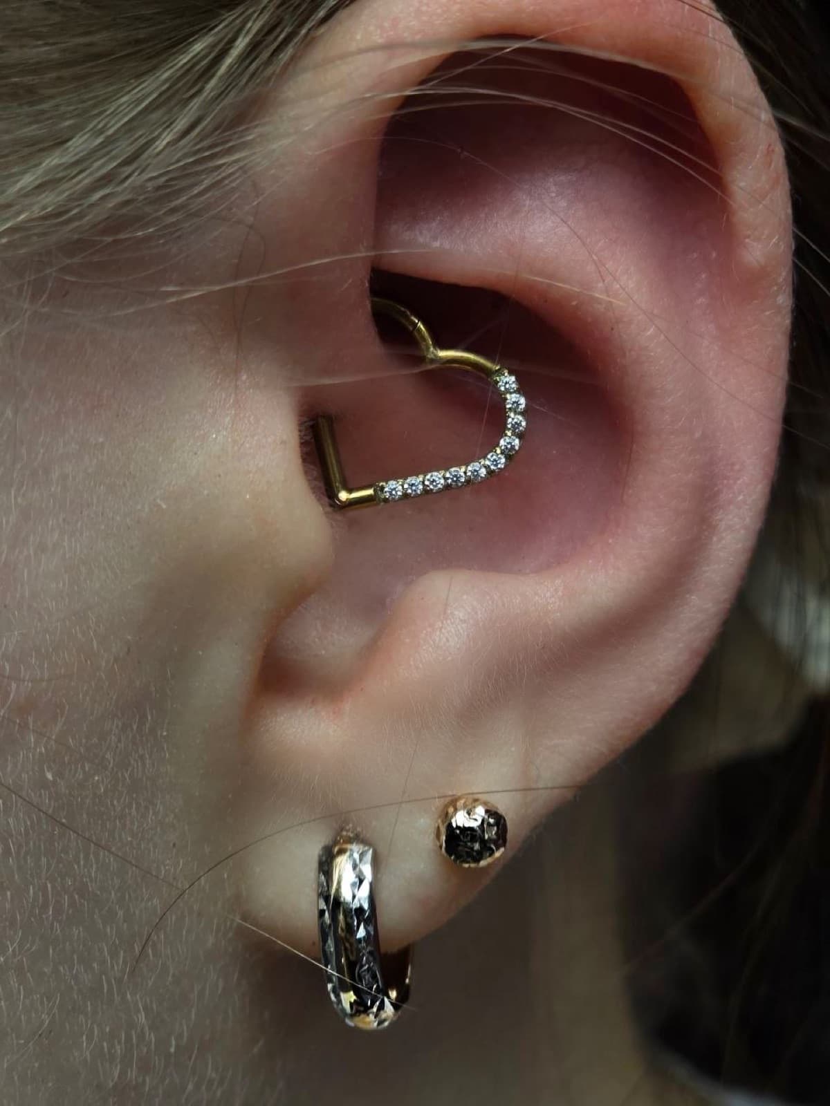 Conch piercing with a gold heart-shaped crystal hoop