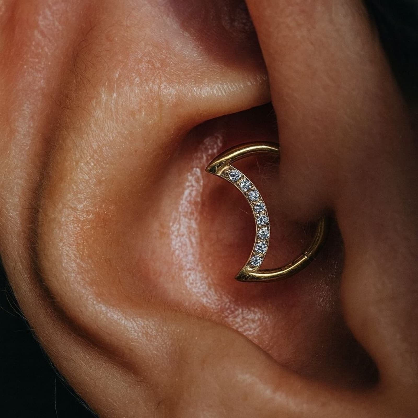 Conch piercing with a gold crescent moon hoop