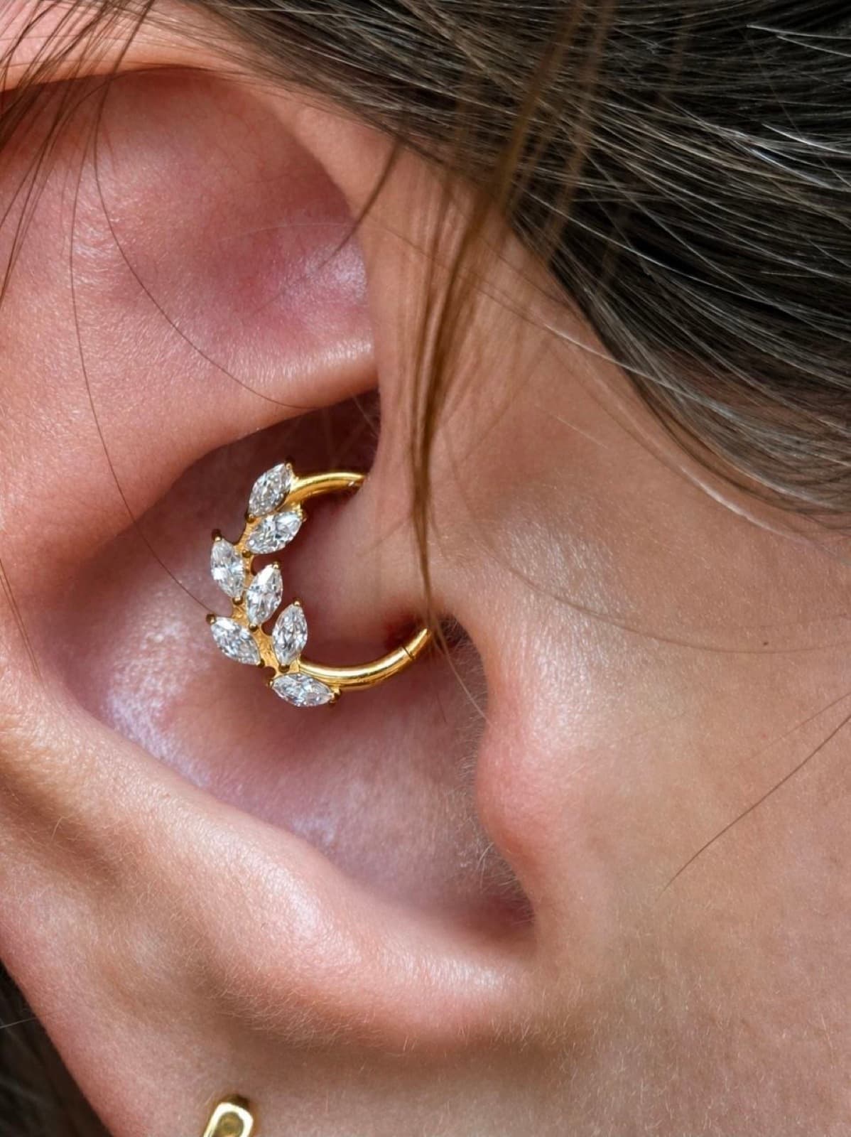 Daith piercing with a gold leaf-cluster hoop