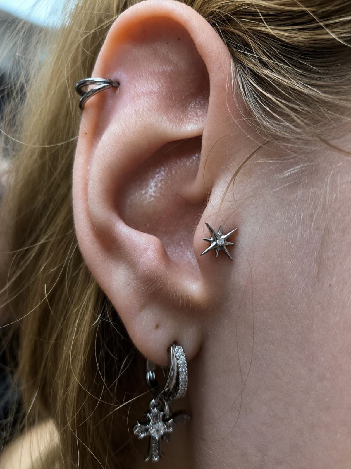 Helix piercing with a star stud and lobe hoop earrings