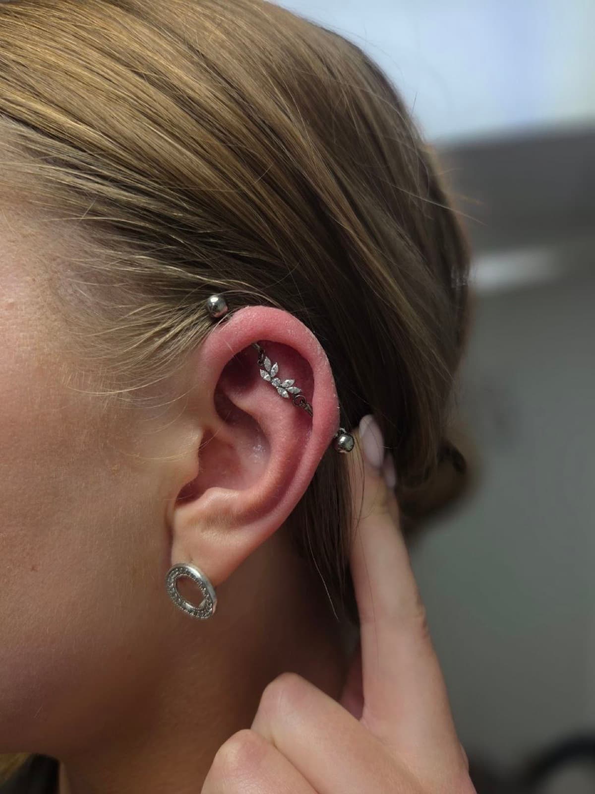 Rook piercing with a cross charm huggie earring