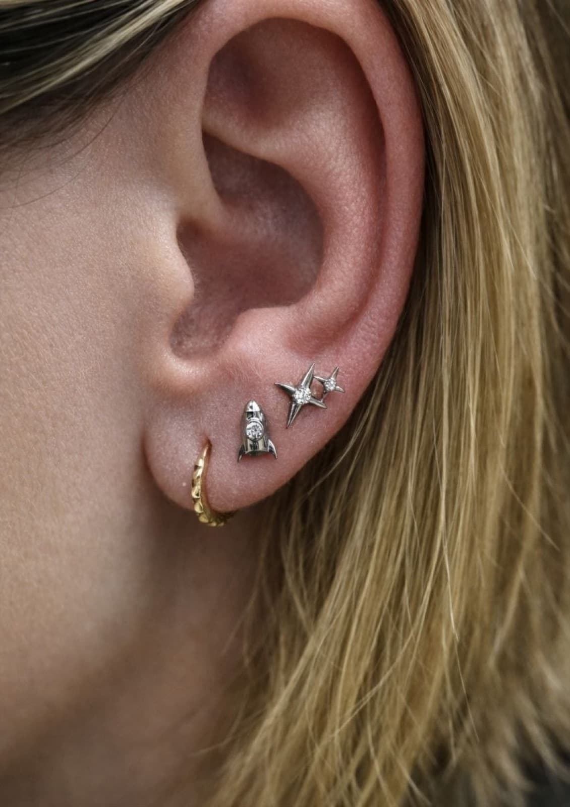 Lobe piercing with rocket and starburst stud earrings