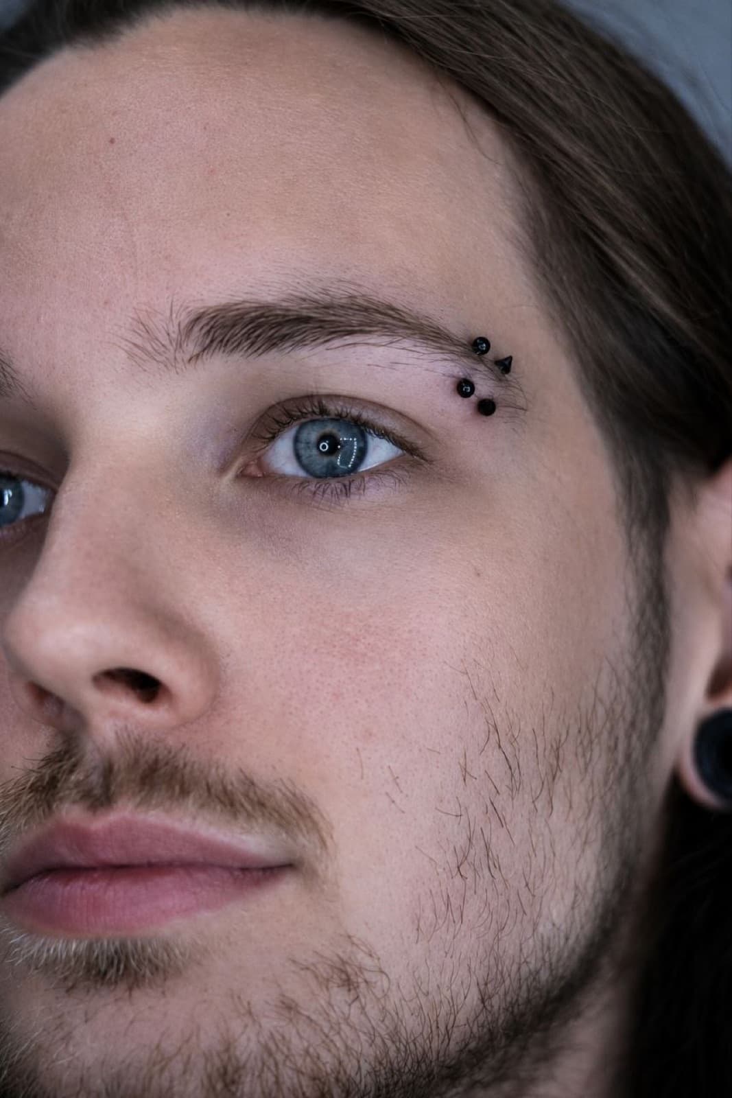 Double eyebrow piercing with silver ball studs