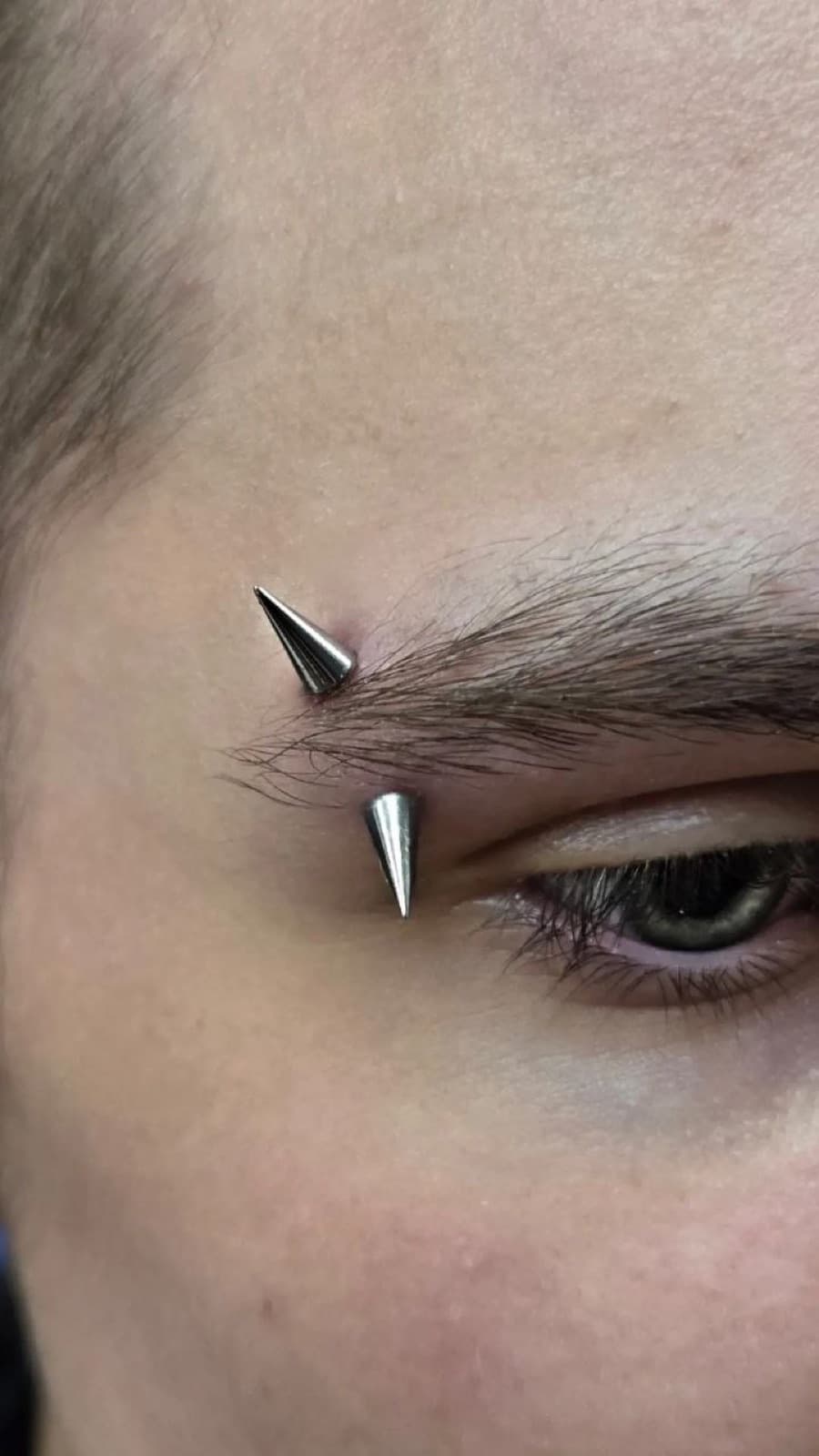 Double eyebrow piercing with spike-top barbells