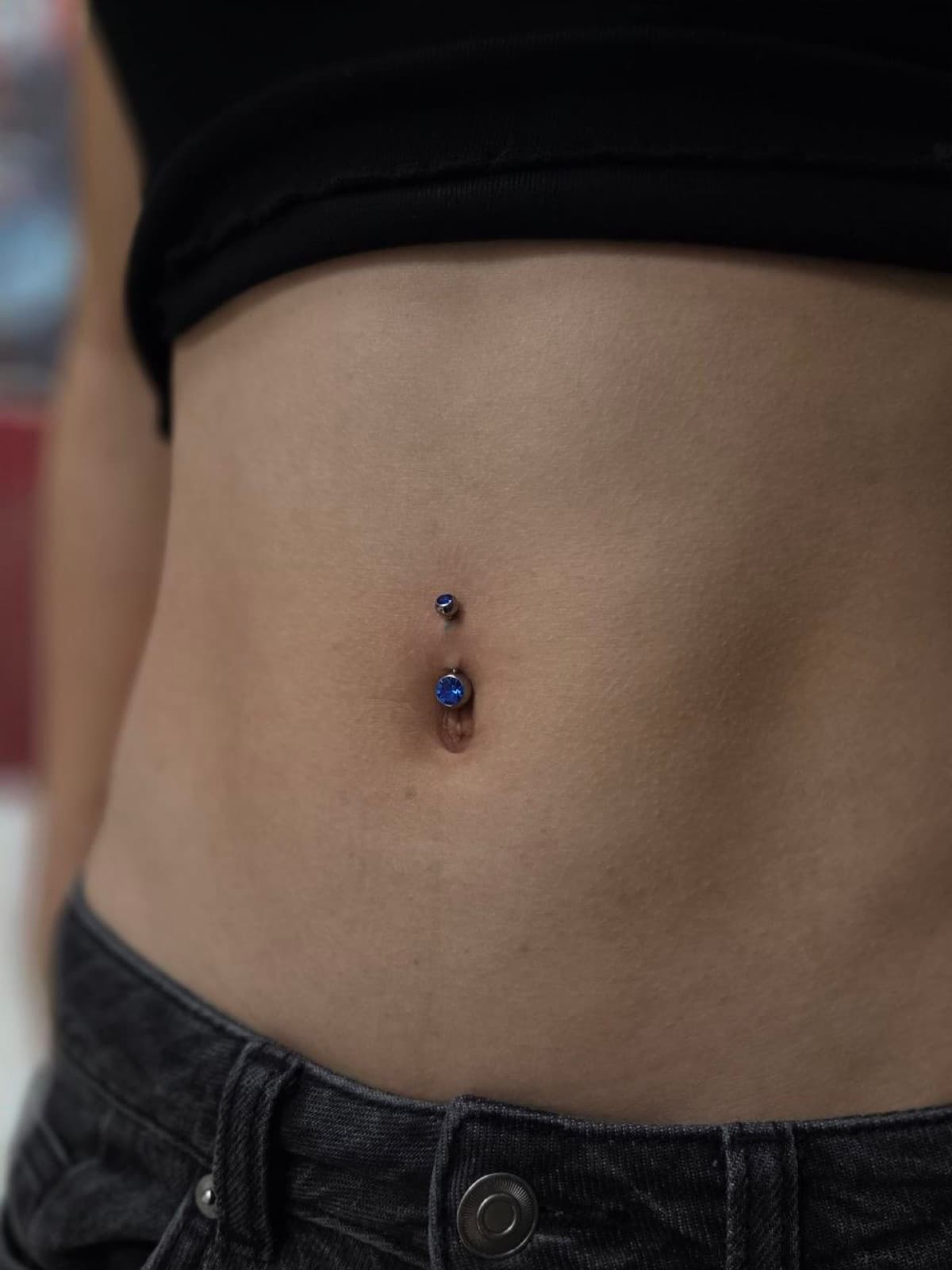 Navel piercing with a blue gemstone barbell
