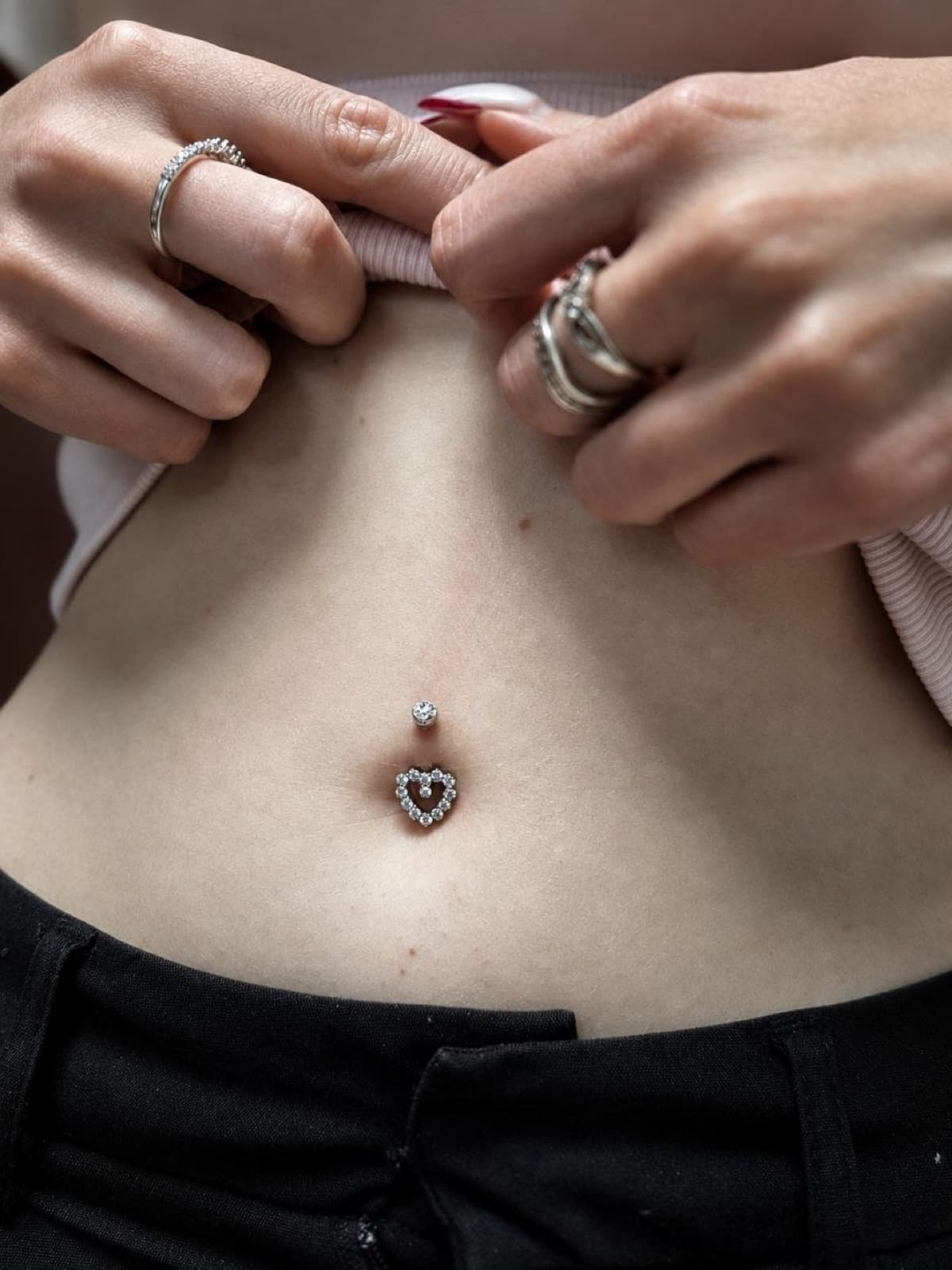 Navel piercing with a heart-shaped charm