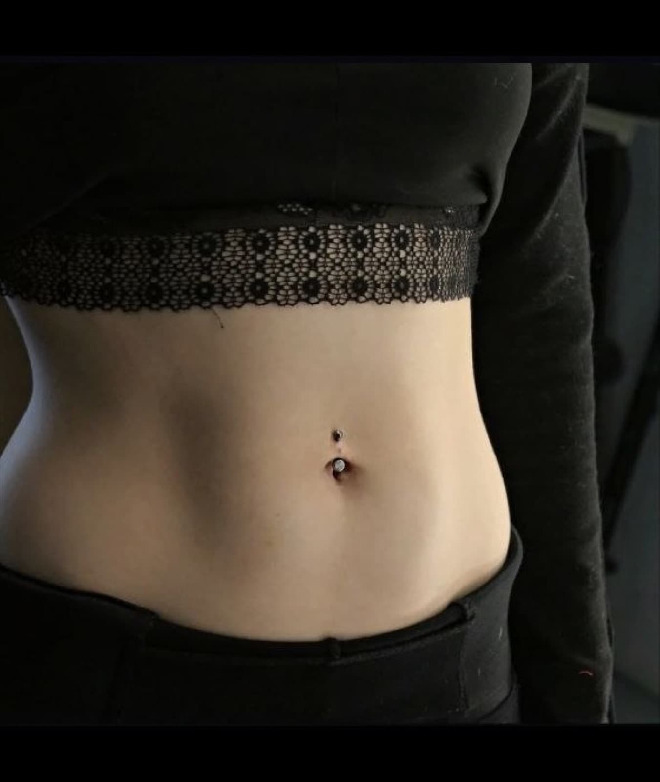 Navel piercing with a single crystal barbell, black lace crop top
