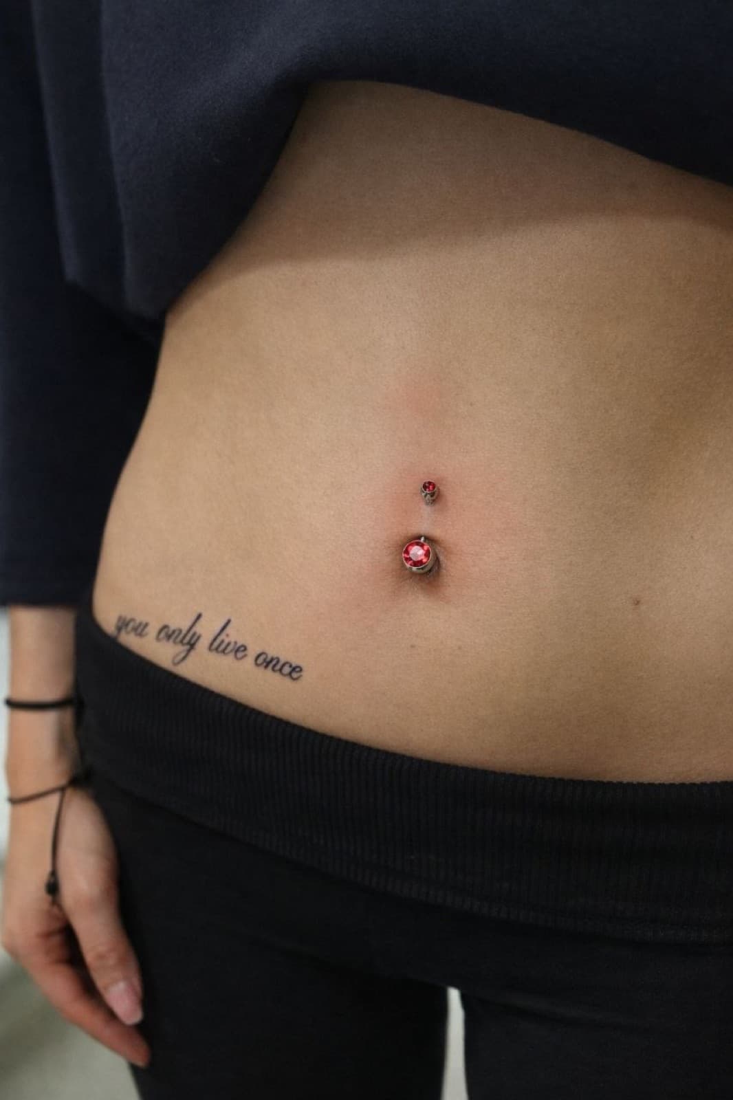 Navel piercing with a red gem curved barbell