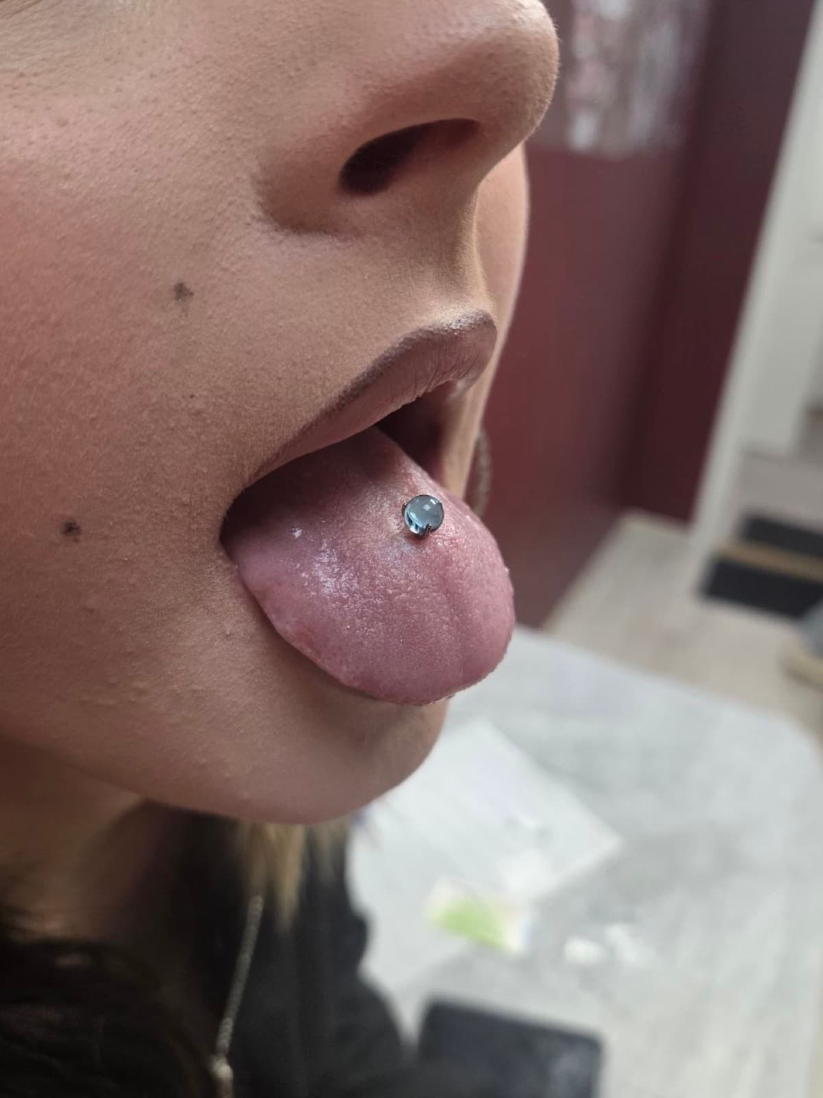 Classic tongue piercing with a blue gem barbell